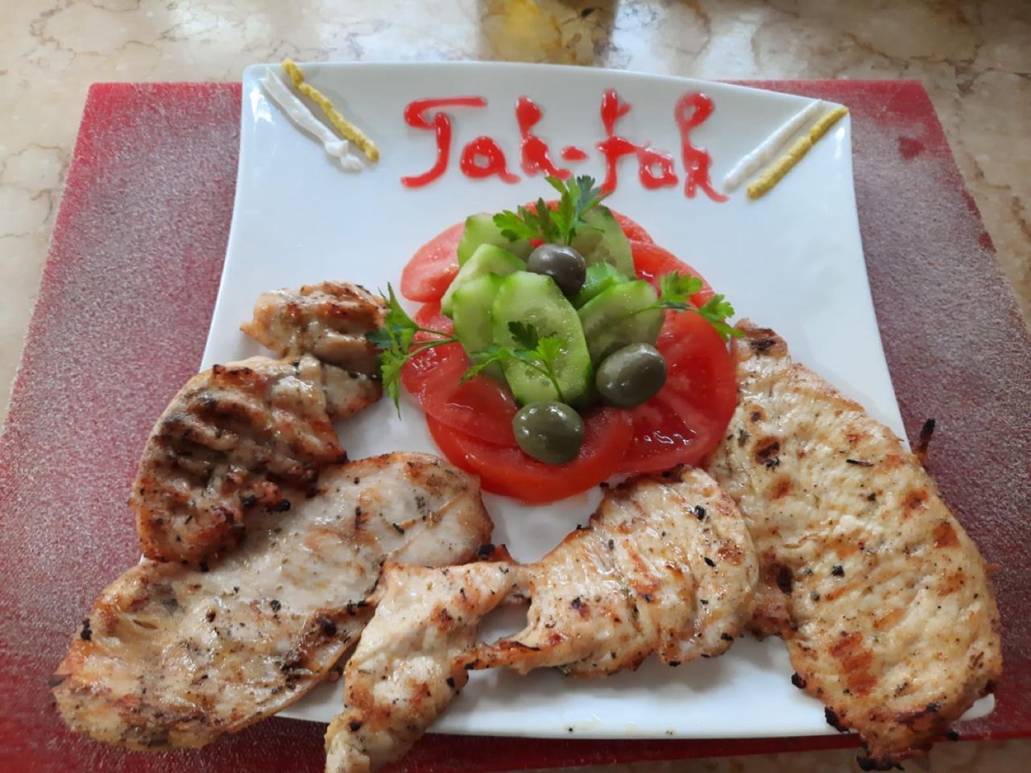 Grilled chicken fillets with the Tak-Fak name written in sauce